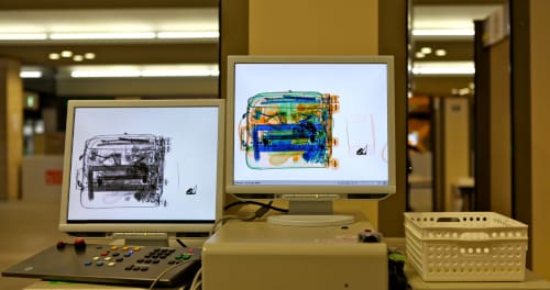 Two computer screens showing a scan of the inside of a suitcase