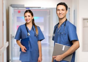 Two nurses holding clipboards standing in a hallway.