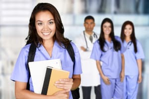 A nurse holding notebooks and wearing a backpack with doctors and nurses in the background.