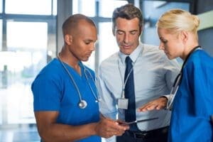 A doctor and two nurses looking at a tablet.