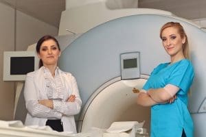 Radiologic technician smiling at mature female patient lying on a MRI Scan bed