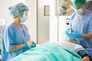 Portrait of a female nurse holding the hand of a patient before he is put under the effect of anesthesia for surgery