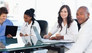 Members of a medical team looking at the camera while working on a laptop