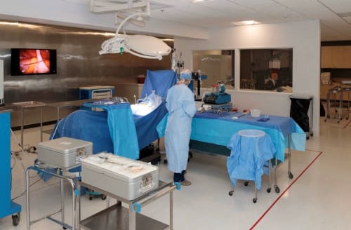 A surgical tech student practicing in a classroom with surgical equipment