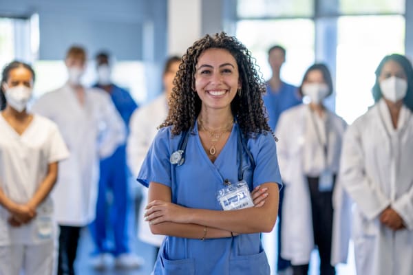 A nurse standing with her arms crossed standing in front of a group of doctors