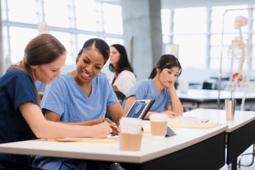 Multiple RN to BSN students studying together in a classroom.