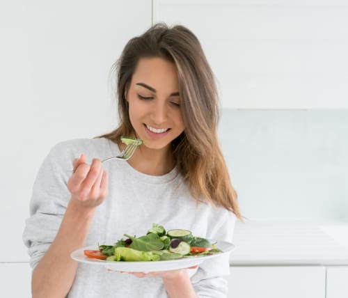Nursing student in her kitchen eating a salad.
