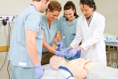 Student nurses working with an instructor on a dummy to learn intubation