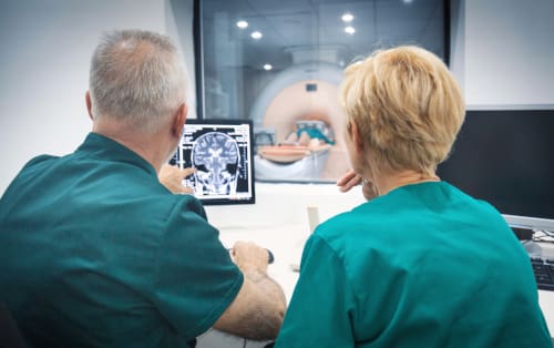 An MRI Technician and a doctor examining the results of an MRI scan.