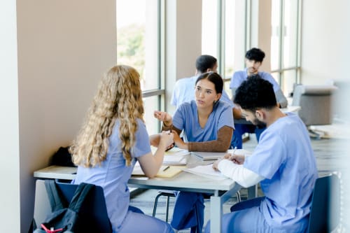 A group of three nursing students sitting at a table and studying notes