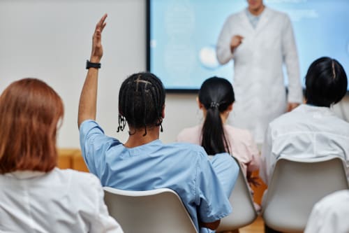 A group of surgical technicians in a classroom with an instructor at the front.