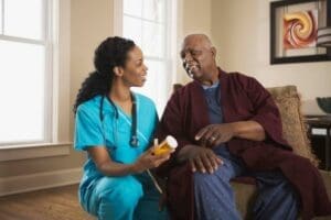 A nurse sitting with an older man at his home