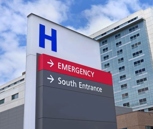 A sign in front of a hospital with a large H on it