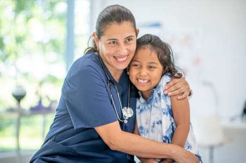 A school nurse giving a student a hug.