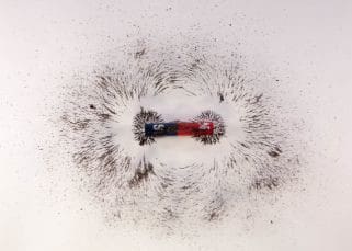 A magnet with iron filings surrounding it in a circular pattern