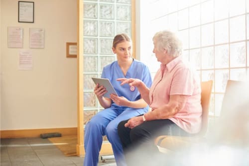 A nurse sitting with a patient in the waiting room of a doctor's office