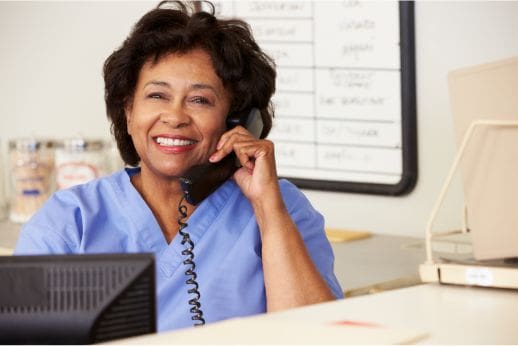 A nurse sitting at a desk and talking on a phone