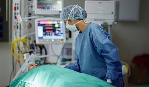 A surgical technician talking to a patient laying on a bed after surgery