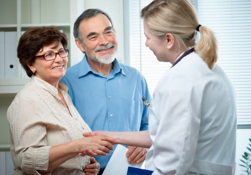 A nurse shaking hands with an older couple