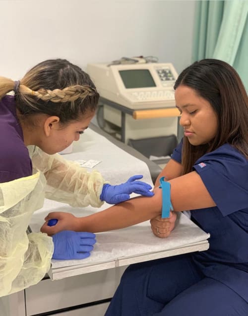 A nursing student practicing taking blood on another student