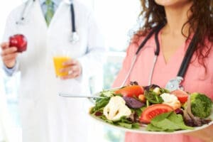 A nurse holding a salad and a doctor holding an apple