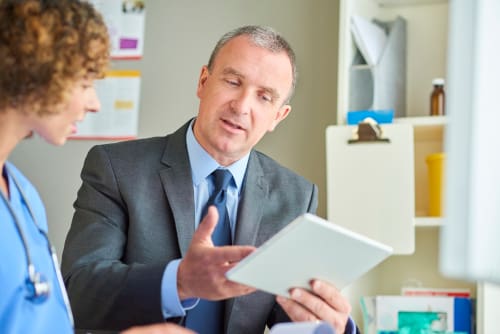 A nurse discussing information with a man in a suit