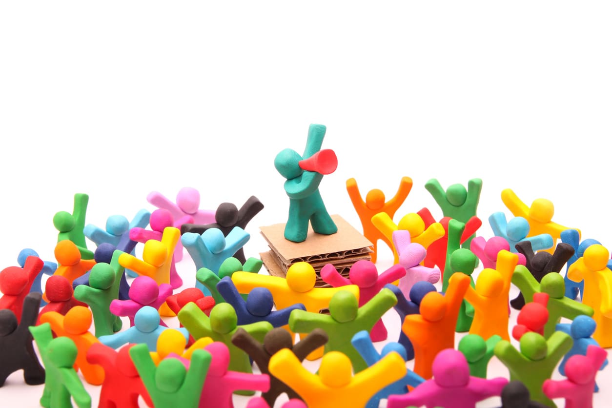 Multi-color clay figures around one figure with a megaphone