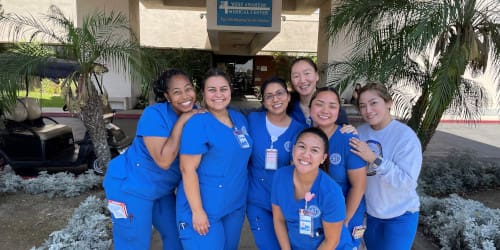 Seven CNI College RN students standing in front of a hospital